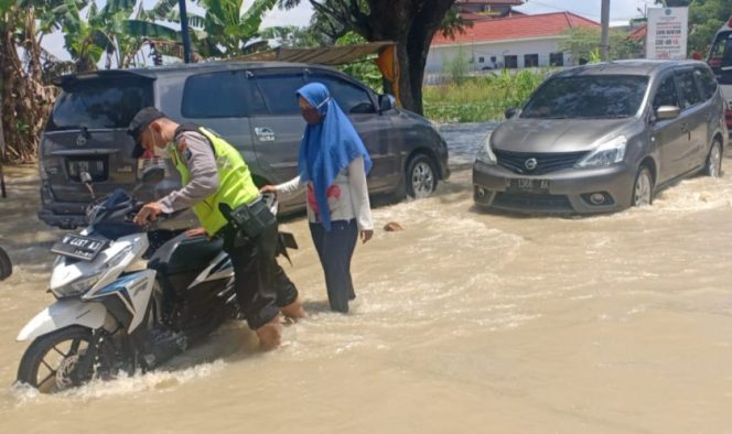
					Jalan Terendam Banjir, Anggota Polsek Benjeng Gresik Dorong Motor Mogok Warga