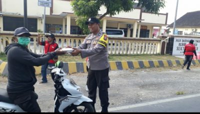 Aipda Samsul Arifin, bagikan nasi kotak kepada warga pengendara motor yang kebetulan melintas di depan kantor Polsek Puger