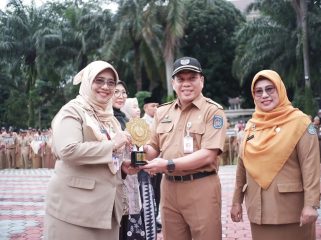 Sekda Kota Depok Mangguluang Mansur menyerahkan penghargaan UHC Award tingkat nasional kepada Kepala Dinkes Kota Depok Devi Maryori.