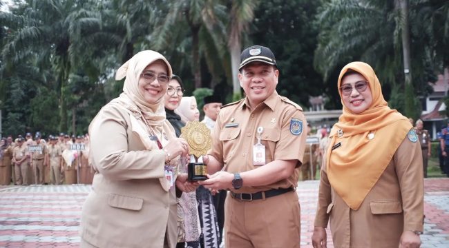 Sekda Kota Depok Mangguluang Mansur menyerahkan penghargaan UHC Award tingkat nasional kepada Kepala Dinkes Kota Depok Devi Maryori.